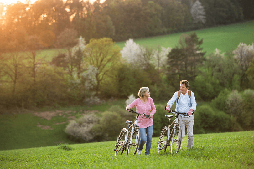 Couple walking bikes in nature Couple walking bikes in nature